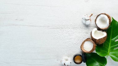 Hindistan cevizi ve tropikal yapraklara dayalı kozmetik ürünler. Beyaz ahşap bir arka planda. Düz yatıyordu.