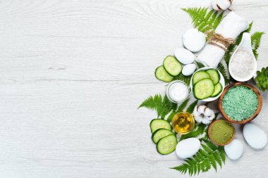 Yeşil salatalıktan doğal kozmetik ürünleri, beyaz ahşap arka planda. Kozmetik ve spa konsepti. Üst Manzara. Boş kopyalama alanı.