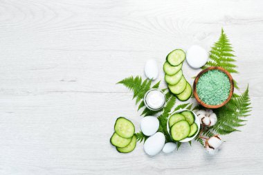 Yeşil salatalıktan doğal kozmetik ürünleri, beyaz ahşap arka planda. Kozmetik ve spa konsepti. Üst Manzara. Boş kopyalama alanı.