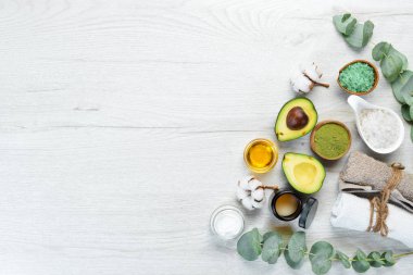Avokado, avokado yağı, deniz tuzu ve yüz kremi, beyaz ahşap arka planda. Kozmetik ve spa konsepti. Üst Manzara. Boş kopyalama alanı.