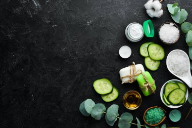 Yeşil salatalıktan kozmetik ürünleri, siyah taş arka planda. Kozmetik ve spa konsepti. Üst Manzara. Boş kopyalama alanı.