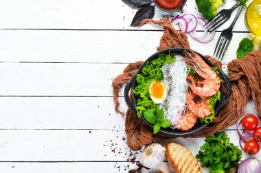 Siyah taşlı arka planda siyah tabakta karidesli erişte, yumurta ve yeşillik. Üst Manzara. Metnin için boş yer.