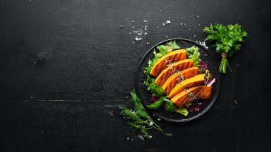 Kabak çekirdekli fırınlanmış balkabağı ve siyah arka planda siyah bir tabakta susam tohumları. Üst Manzara. Metnin için boş yer.