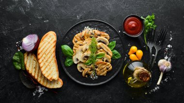 Beyaz ahşap arka planda siyah bir tabakta susamlı ve fesleğenli kızarmış mantar. Üst Manzara. Metnin için boş yer.