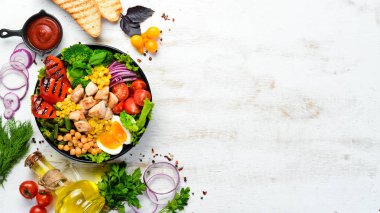 Buda kasesi: Tavuk, nohut, brokoli, domates, yumurta, kırmızı biber, siyah arkaplanda siyah bir tabakta soğan. Üst Manzara. Metnin için boş yer.