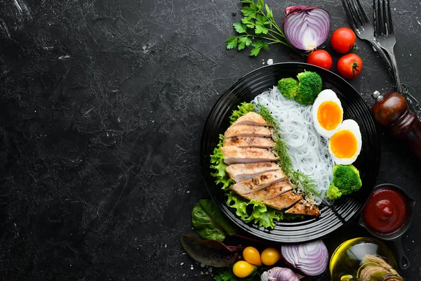 Reisnudeln Mit Hühnerfilet Und Brokkoli Auf Einem Schwarzen Teller Auf — Stockfoto