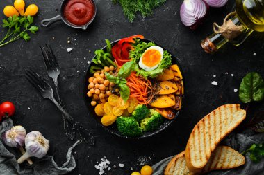 Buddha bowl: pumpkin, broccoli, egg, tomatoes, carrots, paprika in a black plate on a white wooden background. Top view. Free space for your text. clipart