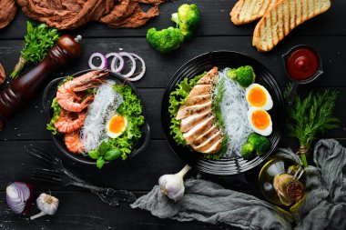 Siyah arka planda siyah tabakta pirinç eriştesi. Asya mutfağı. Üst Manzara. Metnin için boş yer.