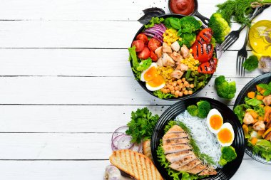 Siyah arka planda siyah tabakta tavuk eti ve sebze tabakları. Buda kasesi. Üst Manzara. Metnin için boş yer.