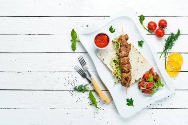 Pita ekmeği ve sebzeli ızgara et şişleri. Et kebabı. Bulaşıklar, yemek. Üst Manzara. Metnin için boş yer.