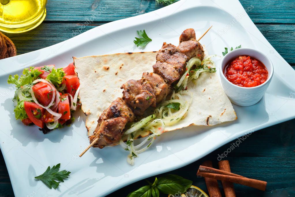 Grilled meat skewers with pita bread and vegetables. Meat kebab. Dishes, food. Top view. Free space for your text.