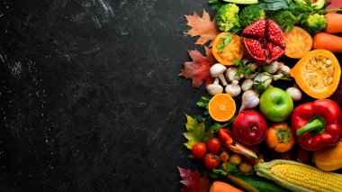 Siyah bir arka planda sonbahar sebzeleri ve meyveler: kabak, domates, mısır, nar, hurma, elma. Üst Manzara. Boş kopyalama alanı.