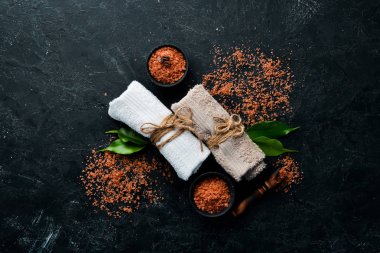 Kahverengi deniz tuzu ve havlular. Siyah taştan bir arka planda. Spa tedavileri. Üst Manzara. Boş kopyalama alanı.
