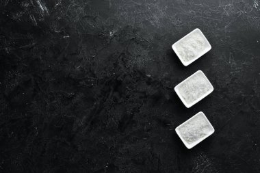 Spa mı? Kasede deniz tuzu. Siyah taştan bir arka planda. Üst Manzara. Metnin için boş yer.