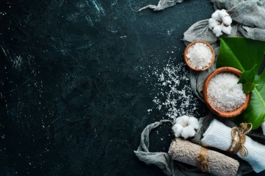 Spa mı? Deniz tuzu ve kozmetik havlu. Siyah taştan bir arka planda. Üst Manzara. Metnin için boş yer.