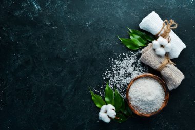 Spa mı? Deniz tuzu ve kozmetik havlu. Siyah taştan bir arka planda. Üst Manzara. Metnin için boş yer.