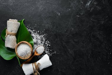 Spa mı? Deniz tuzu ve kozmetik havlu. Siyah taştan bir arka planda. Üst Manzara. Metnin için boş yer.
