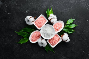 Kozmetik pembe deniz tuzu. Siyah taştan bir arka planda. Spa tedavileri. Üst Manzara. Metnin için boş yer.