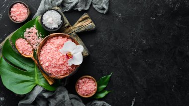 Bir kasede pembe kokulu deniz tuzu. Siyah taştan bir arka planda. Spa tedavileri. Üst Manzara. Metnin için boş yer.