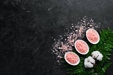 Bir kasede pembe kokulu deniz tuzu. Siyah taştan bir arka planda. Spa tedavileri. Üst Manzara. Metnin için boş yer.