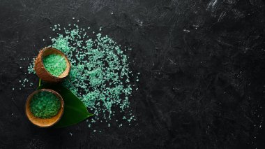 Kasede yeşil deniz tuzu. Siyah taştan bir arka planda. Spa tedavileri. Üst Manzara. Metnin için boş yer.