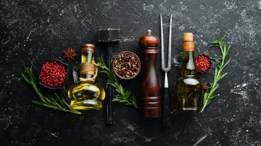 Siyah taş bir masada baharatlar, bitkiler ve yağ. Üst Manzara. Metnin için boş yer.