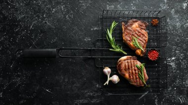 Siyah taştan bir masada ızgara biftek ve baharat. Üst Manzara. Metnin için boş yer.
