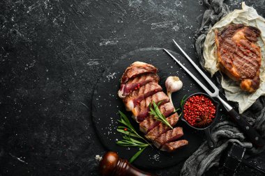 Biberiyeli ızgara biftek ve siyah taşlı arka planda baharatlar. Üst Manzara. Metnin için boş yer.