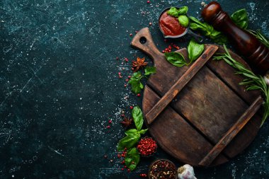 Siyah taşlı arka planda baharatlar ve otlarla dolu mutfak tahtası. Üst Manzara. Metnin için boş yer.