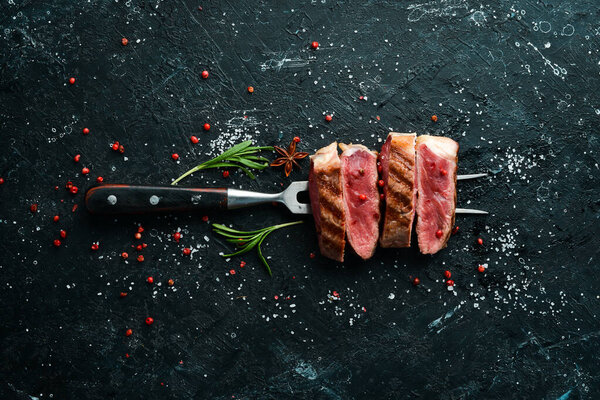 Grilled ribeye beef steak on the fork. Top view. Free space for your text.