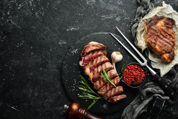Biberiyeli ızgara biftek ve siyah taşlı arka planda baharatlar. Üst Manzara. Metnin için boş yer.