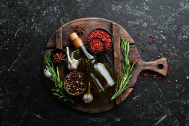 Koyu arkaplanda baharat olan bir kavanoz zeytinyağı. Üst Manzara. Metnin için boş yer.