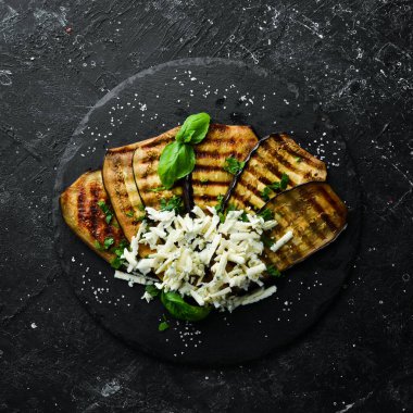 Yiyecekler. Fırında patlıcan, mavi peynirli ve fesleğenli siyah taş tabakta. Üst Manzara. Metnin için boş yer.