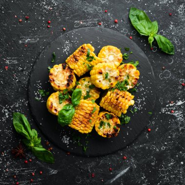 Yiyecekler. Siyah taş tabakta maydanozlu ve fesleğenli fırında mısır. Üst Manzara. Metnin için boş yer.