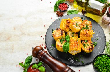 Yiyecekler. Siyah taş tabakta maydanozlu ve fesleğenli fırında mısır. Üst Manzara. Metnin için boş yer.