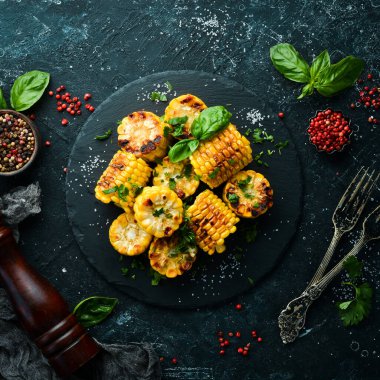 Yiyecekler. Siyah taş tabakta maydanozlu ve fesleğenli fırında mısır. Üst Manzara. Metnin için boş yer.