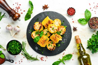 Yiyecekler. Siyah taş tabakta maydanozlu ve fesleğenli fırında mısır. Üst Manzara. Metnin için boş yer.