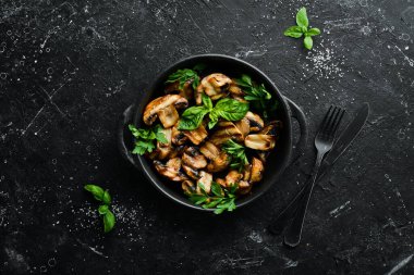 Yiyecekler. Siyah taş tabakta fesleğenli ızgara mantar. Üst Manzara. Metnin için boş yer.