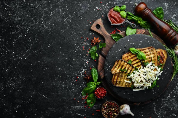 Yiyecekler. Fırında patlıcan, mavi peynirli ve fesleğenli siyah taş tabakta. Üst Manzara. Metnin için boş yer.