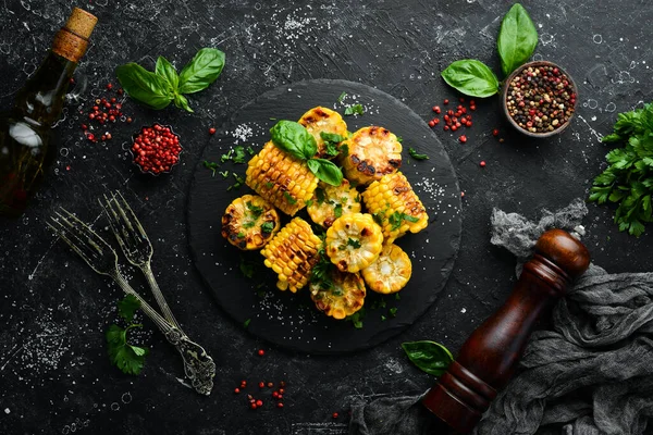 Yiyecekler. Siyah taş tabakta maydanozlu ve fesleğenli fırında mısır. Üst Manzara. Metnin için boş yer.