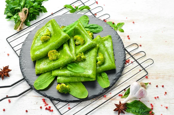 Vejetaryen yemeği. Siyah taş tabakta sebzeli yeşil ıspanaklı krep. Üst Manzara. Metnin için boş yer.