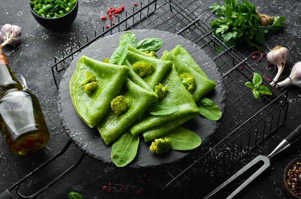 Vejetaryen yemeği. Siyah taş tabakta sebzeli yeşil ıspanaklı krep. Üst Manzara. Metnin için boş yer.