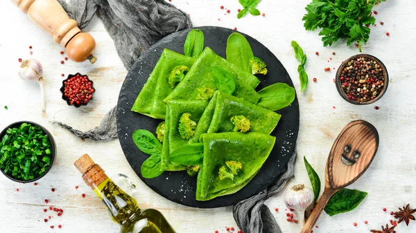 Vejetaryen yemeği. Siyah taş tabakta sebzeli yeşil ıspanaklı krep. Üst Manzara. Metnin için boş yer.