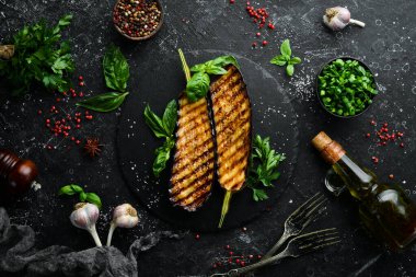 Siyah taş tabakta fesleğenli ızgara patlıcan. Üst Manzara. Metnin için boş yer.