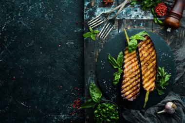 Siyah taş tabakta fesleğenli ızgara patlıcan. Üst Manzara. Metnin için boş yer.