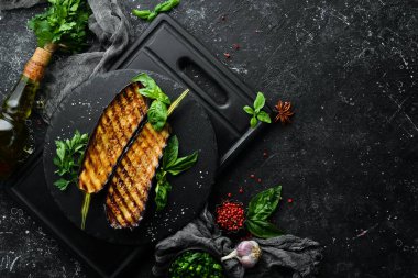 Siyah taş tabakta fesleğenli ızgara patlıcan. Üst Manzara. Metnin için boş yer.