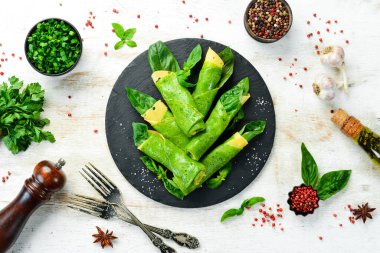 Sağlıklı yiyecekler. Siyah taş tabakta peynirli ve fesleğenli ıspanaklı krep. Üst Manzara. Metnin için boş yer.