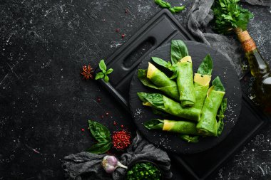 Sağlıklı yiyecekler. Siyah taş tabakta peynirli ve fesleğenli ıspanaklı krep. Üst Manzara. Metnin için boş yer.