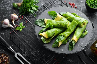 Sağlıklı yiyecekler. Siyah taş tabakta peynirli ve fesleğenli ıspanaklı krep. Üst Manzara. Metnin için boş yer.