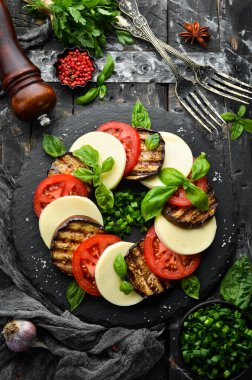 Fesleğenli Caprese salatası. Siyah taş tabakta domates, mozarella peyniri ve patlıcan. Üst Manzara. Metnin için boş yer.